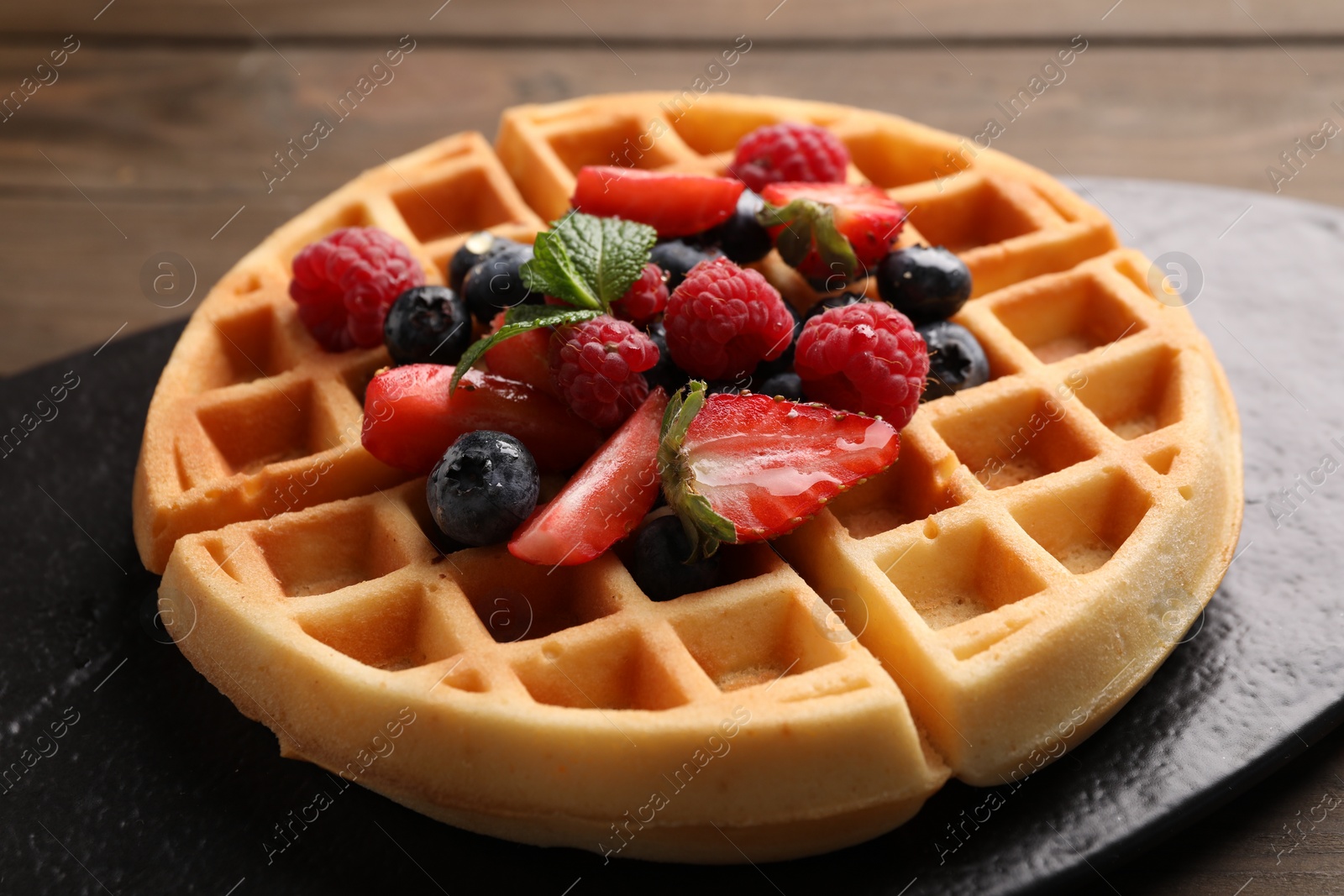 Photo of Tasty Belgian waffle with fresh berries on table, closeup