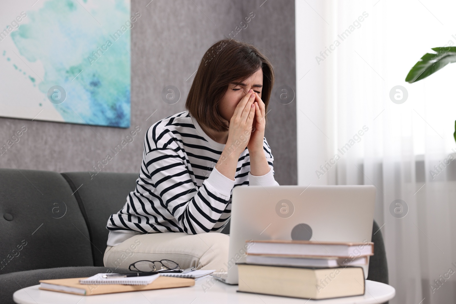 Photo of Overwhelmed woman sitting on sofa at home