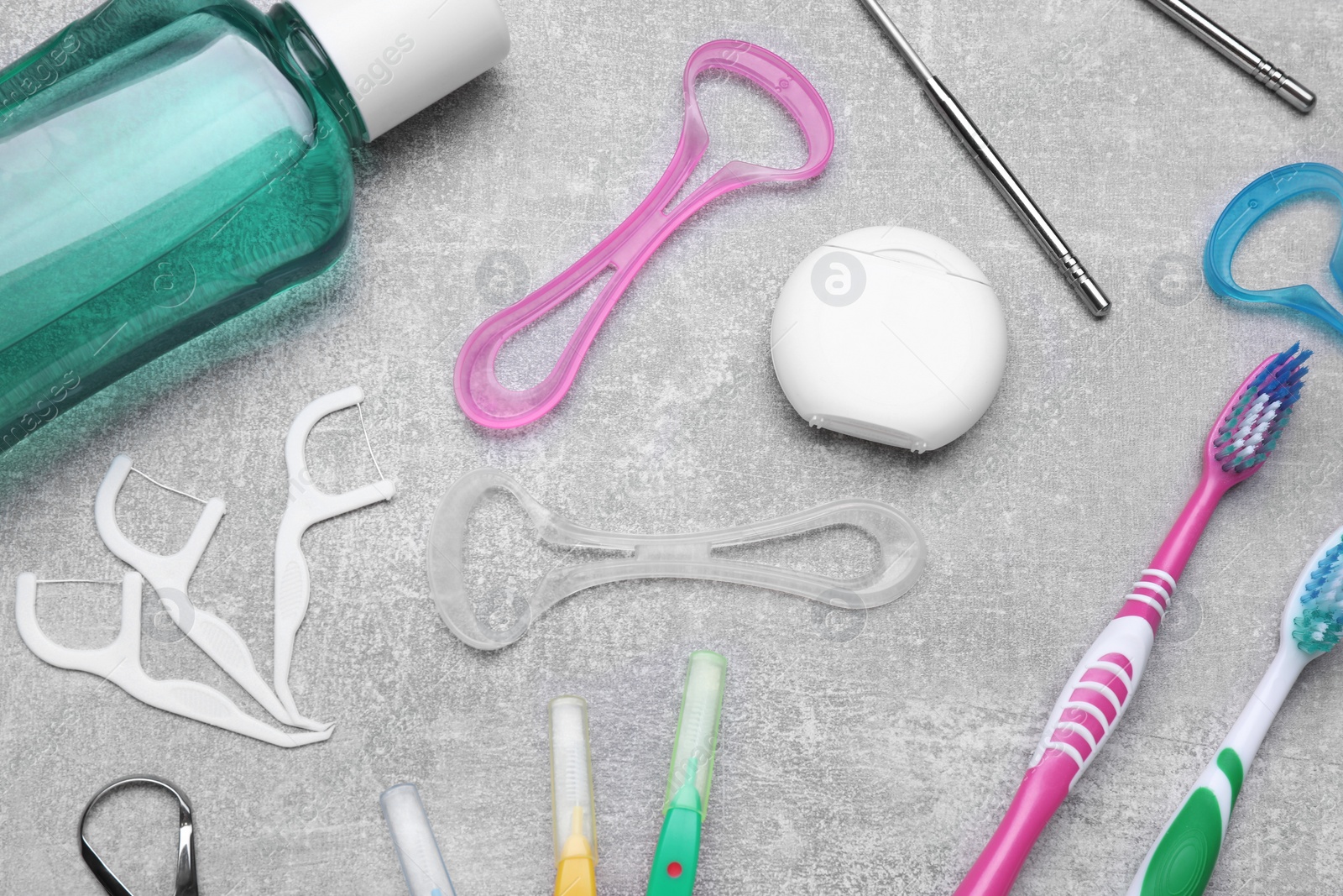 Photo of Tongue cleaners and other oral care products on grey table, flat lay