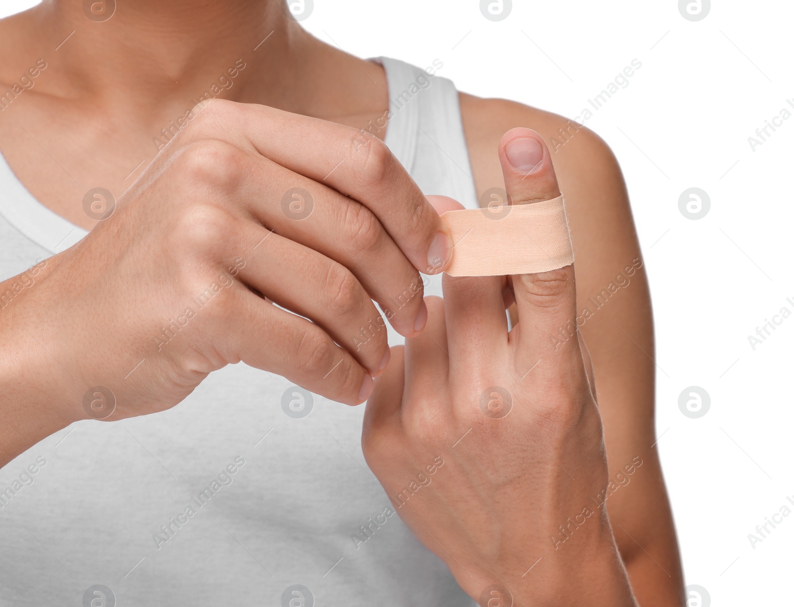 Photo of Man putting sticking plaster onto finger on white background, closeup