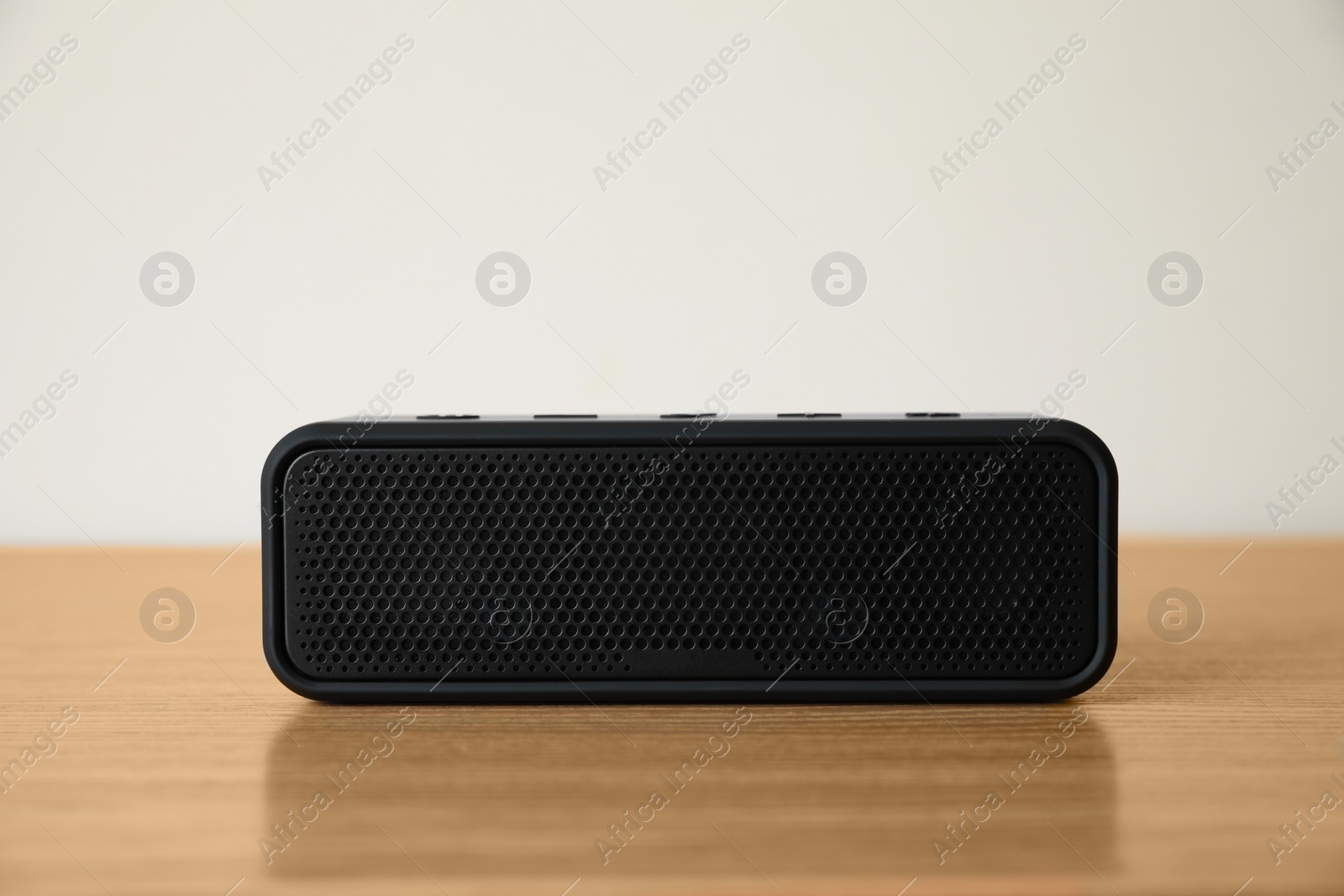 Photo of One black portable bluetooth speaker on wooden table. Audio equipment