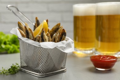 Delicious fried anchovies, sauce and glasses with beer on table. Space for text