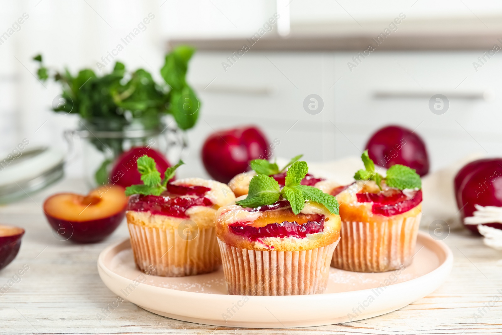 Photo of Delicious cupcakes with plums on white wooden table