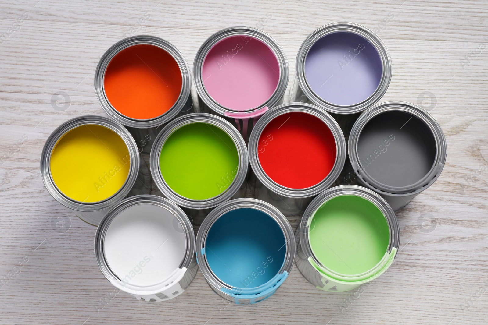 Photo of Cans of different paints on white wooden table, flat lay