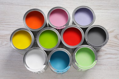Photo of Cansdifferent paints on white wooden table, flat lay