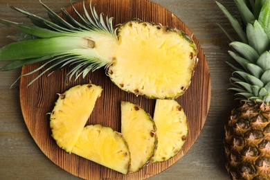 Photo of Whole and cut pineapples on wooden table, flat lay