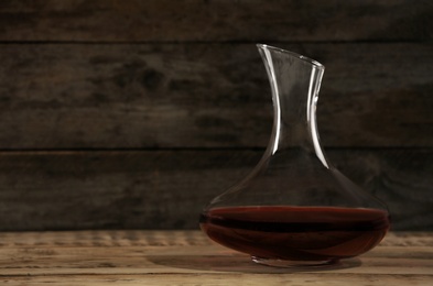 Photo of Elegant decanter with red wine on wooden table