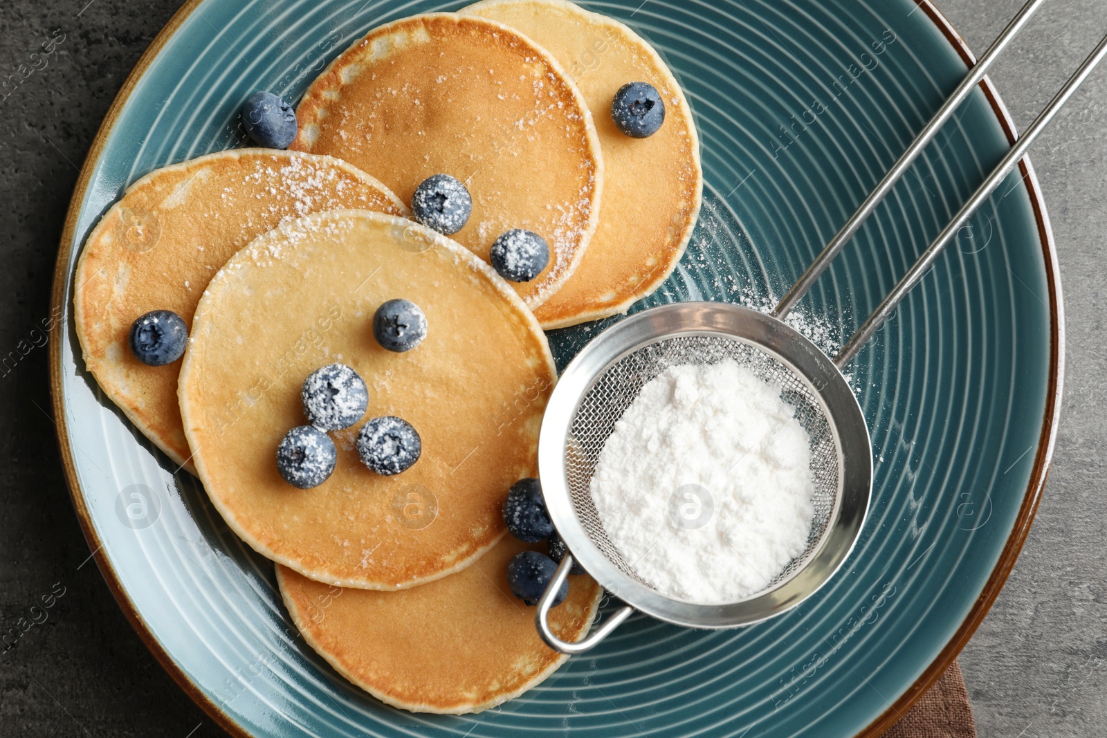 Photo of Plate with pancakes, berries and sugar powder on table, top view