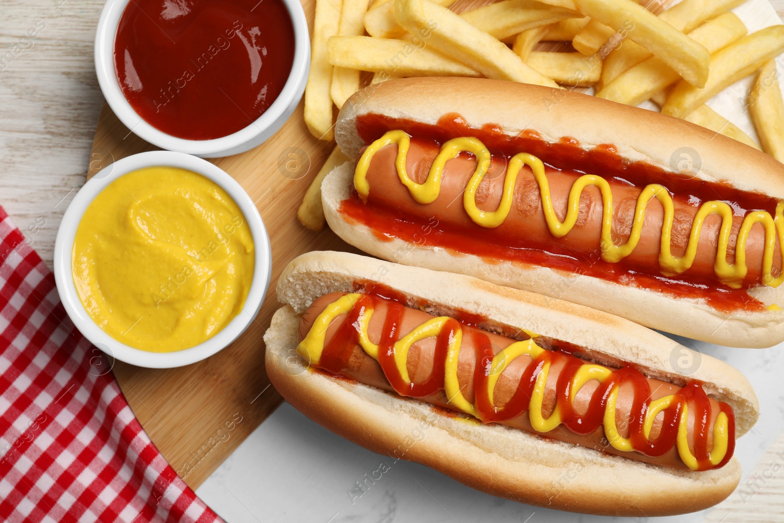 Photo of Delicious hot dogs with mustard, ketchup and potato fries on white wooden table, flat lay