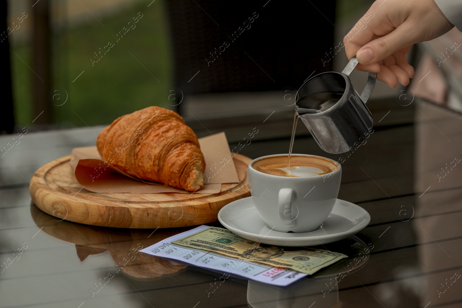 Photo of Waitress pouring coffee from pitcher into cup at table, closeup