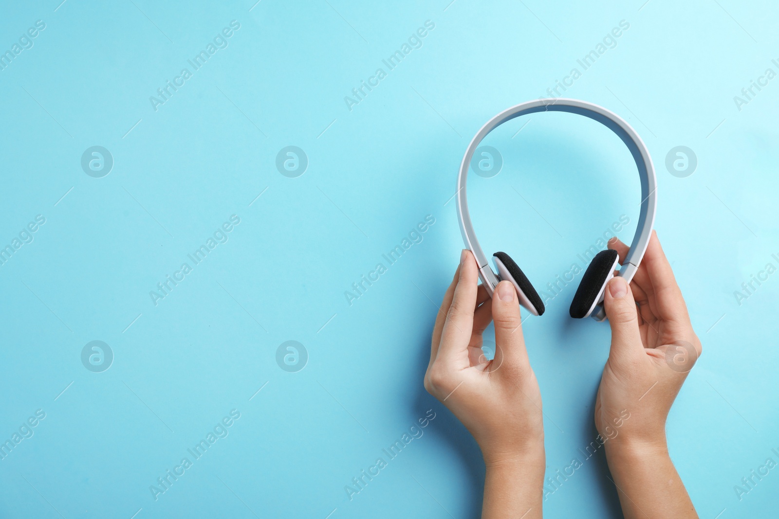 Photo of Woman holding headphones on color background, top view. Space for text