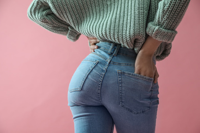 Woman wearing jeans on pink background, closeup