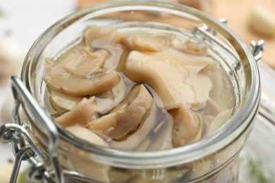 Photo of Glass jar of tasty pickled mushrooms, closeup