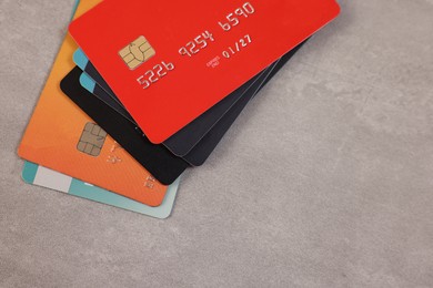Photo of Pile of different credit cards on grey table, top view. Space for text
