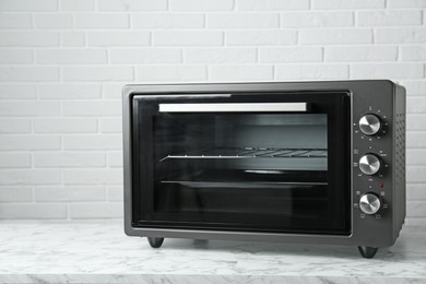 Photo of One electric oven on white marble table near brick wall