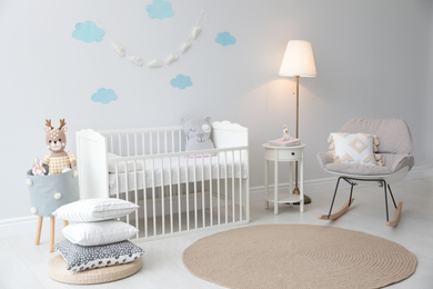 Stylish baby room interior with crib and rocking chair