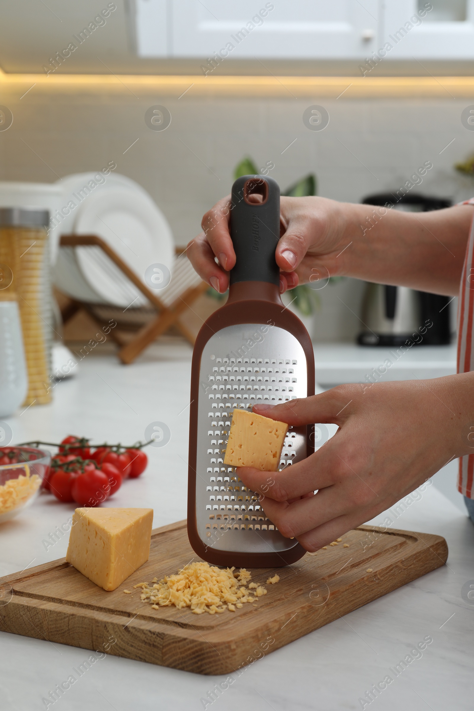 Photo of Woman grating cheese at kitchen counter, closeup