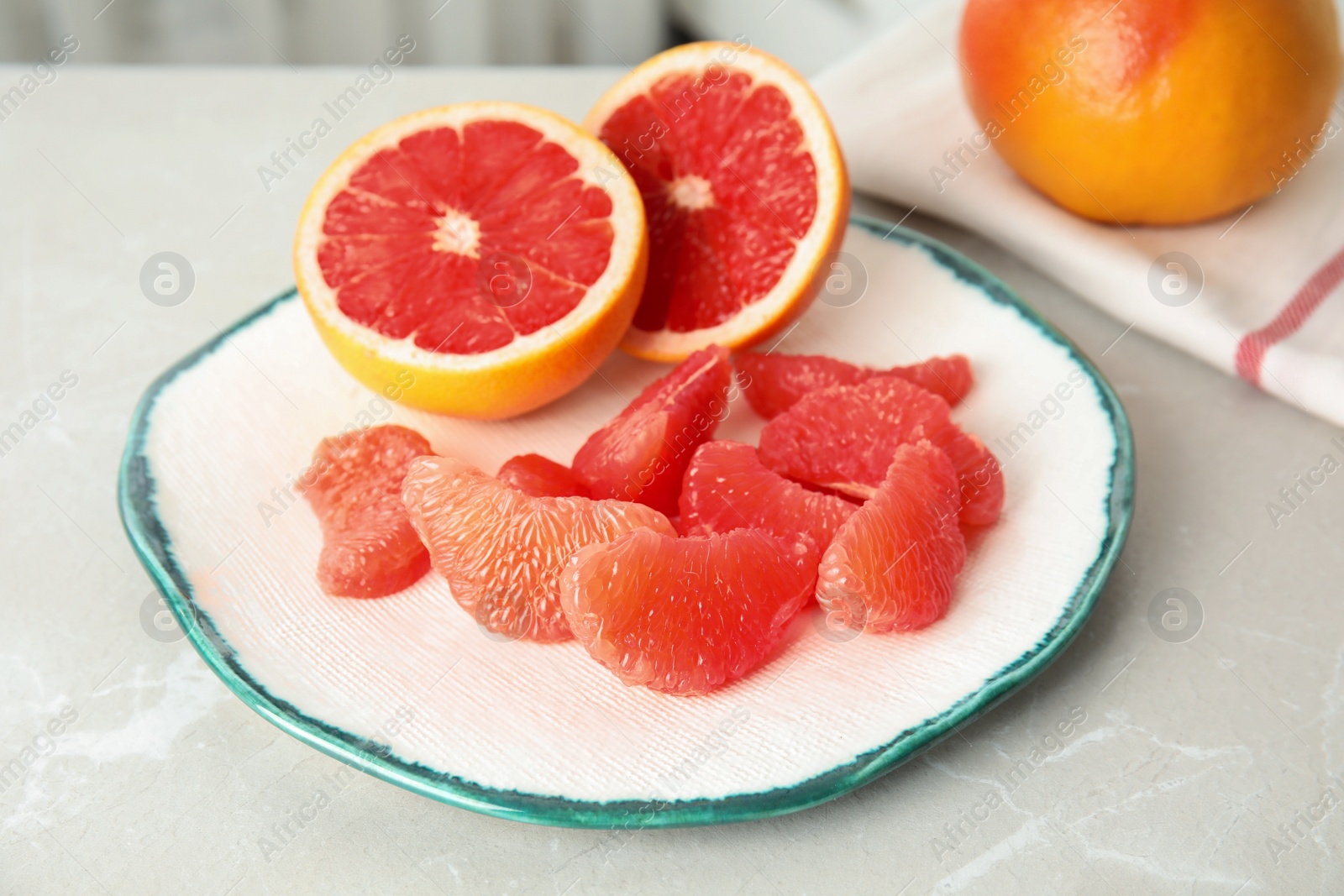 Photo of Plate with yummy grapefruits on grey table