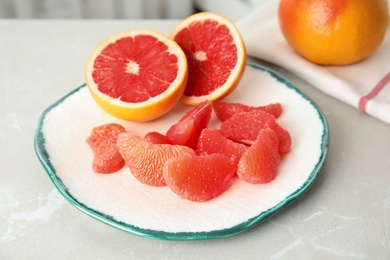 Plate with yummy grapefruits on grey table