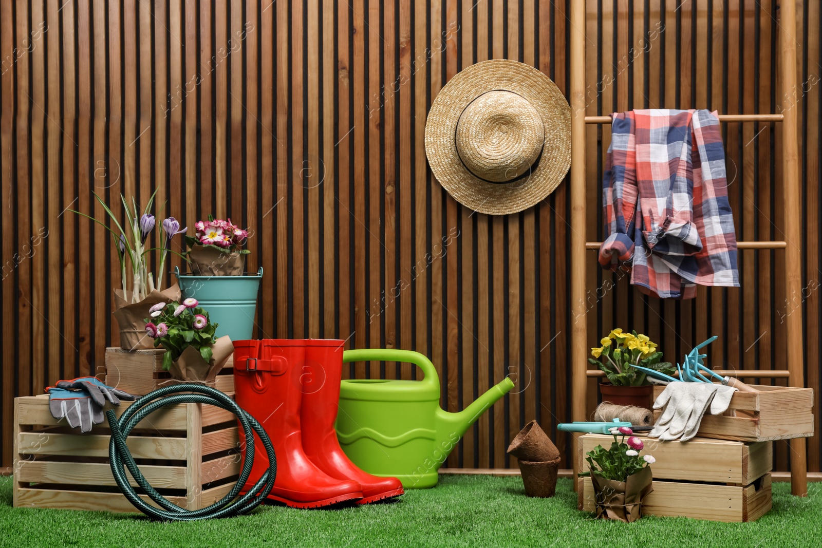 Photo of Composition with different gardening tools on artificial grass at wooden wall. Space for text