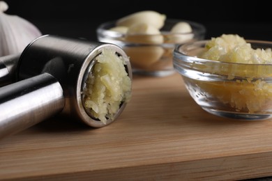 Photo of Garlic press and mince on wooden table, closeup