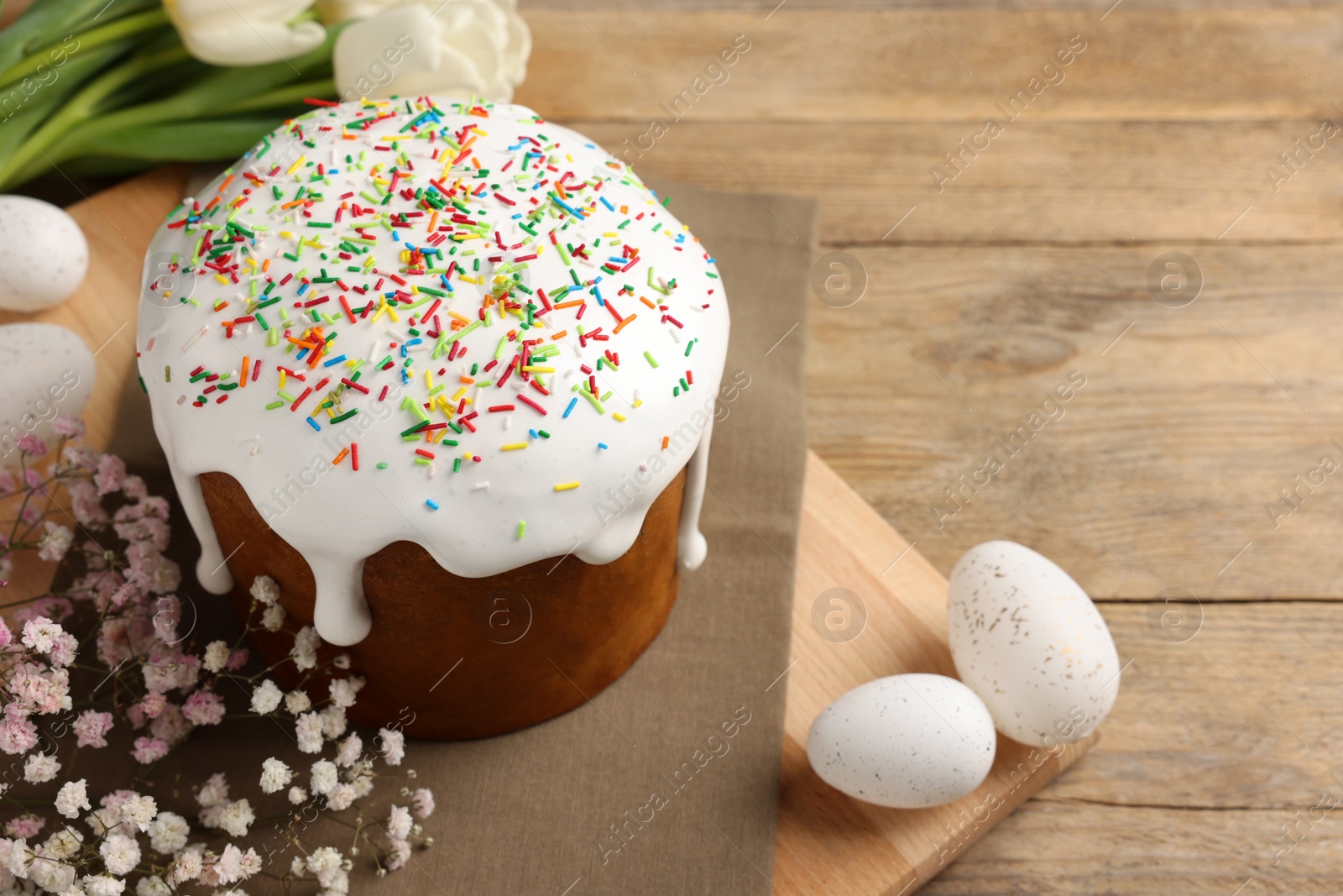 Photo of Tasty Easter cake, decorated eggs and flowers on wooden table. Space for text