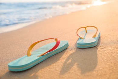 Photo of Bright turquoise beach slippers on sand near sea