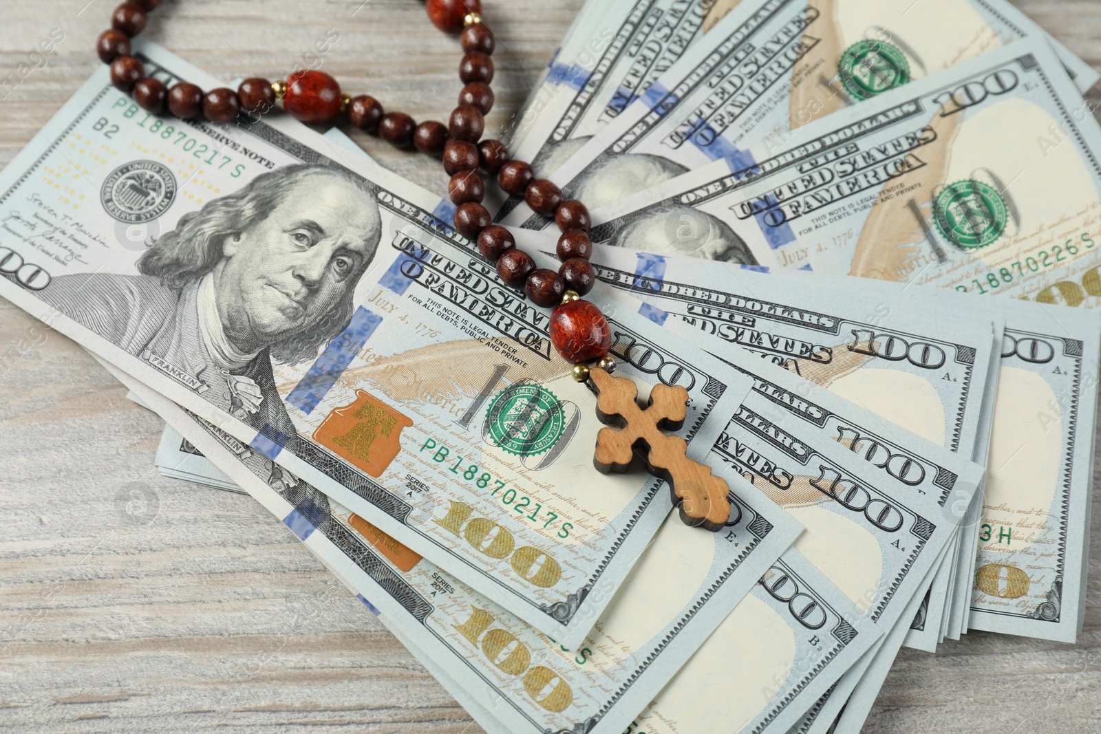 Photo of Cross and money on wooden table, closeup