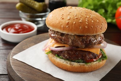 Photo of Tasty hamburger with patties, cheese and vegetables on wooden board, closeup