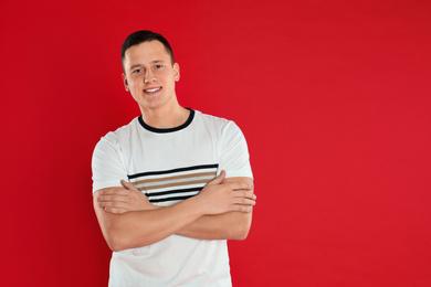 Photo of Happy handsome young man on red background. Space for text