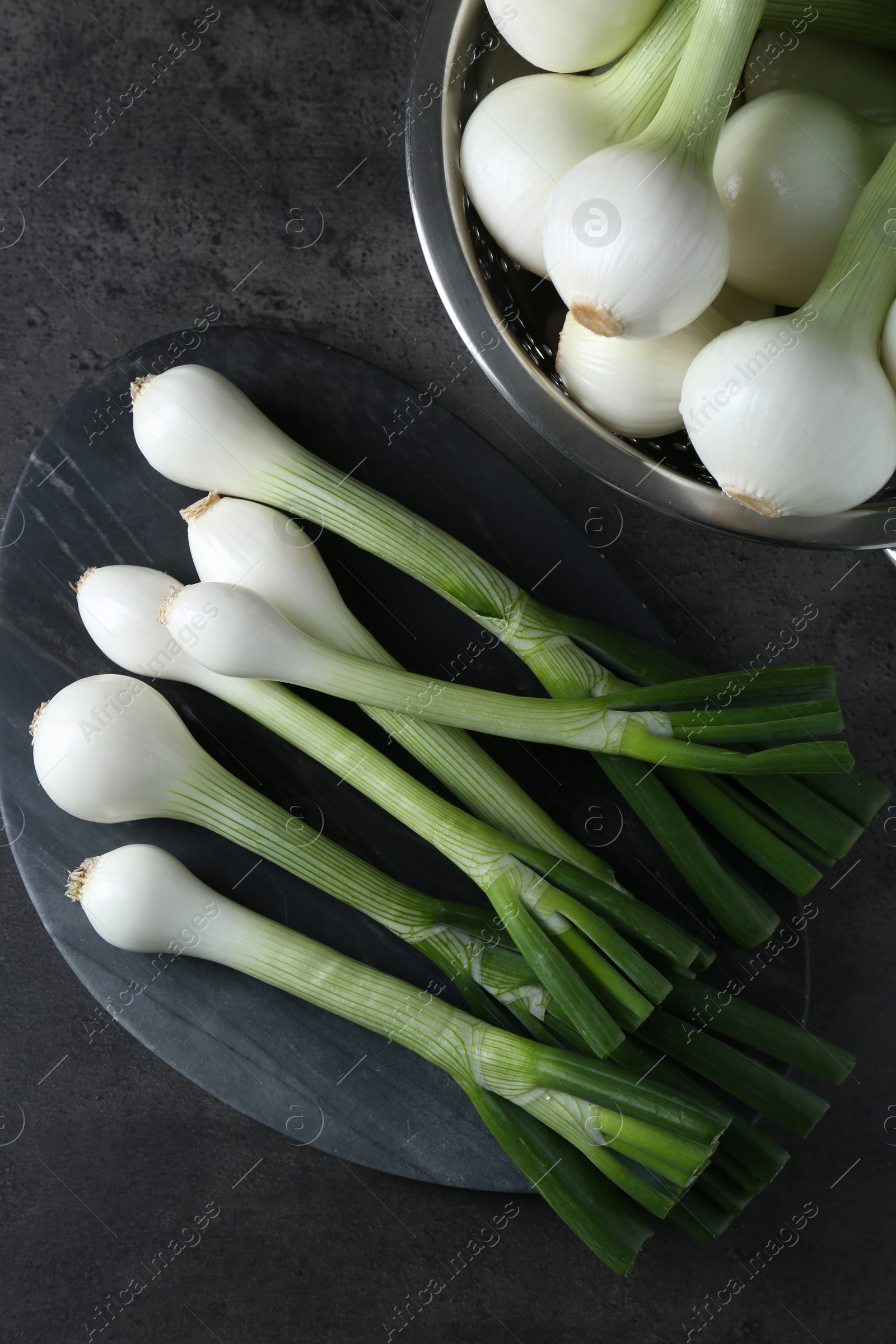 Photo of Whole green spring onions on black table, flat lay