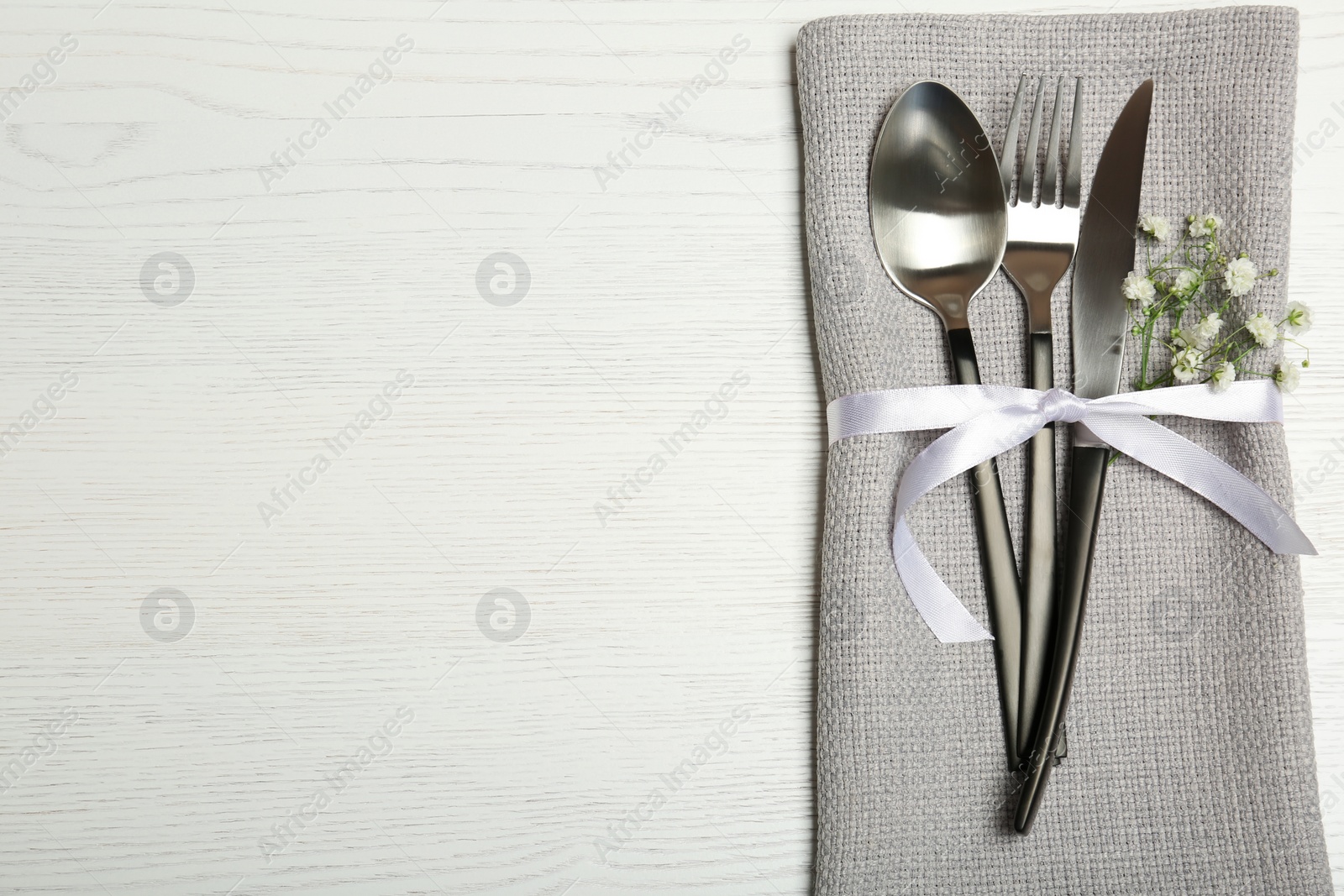 Photo of Cutlery and napkin on light wooden background, top view. Table setting