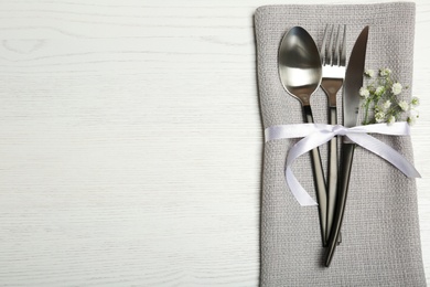 Photo of Cutlery and napkin on light wooden background, top view. Table setting