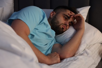 Frustrated man suffering from insomnia in bed