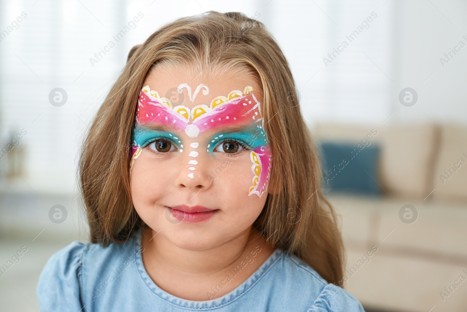 Photo of Cute little girl with face painting indoors