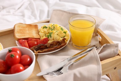 Photo of Good morning. Tray with tasty breakfast on bed
