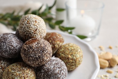 Photo of Different delicious vegan candy balls on plate, closeup