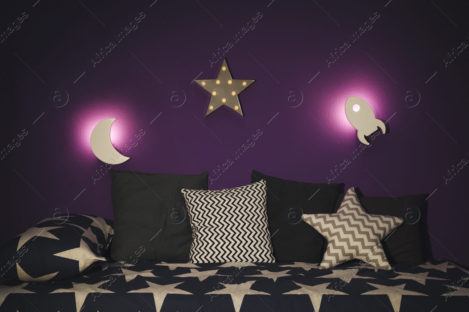 Photo of Room interior with bed and different night lamps on purple wall