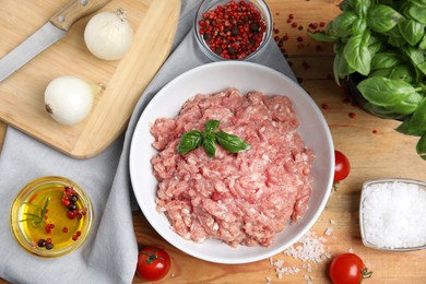 Photo of Raw chicken minced meat and ingredients on wooden table, flat lay