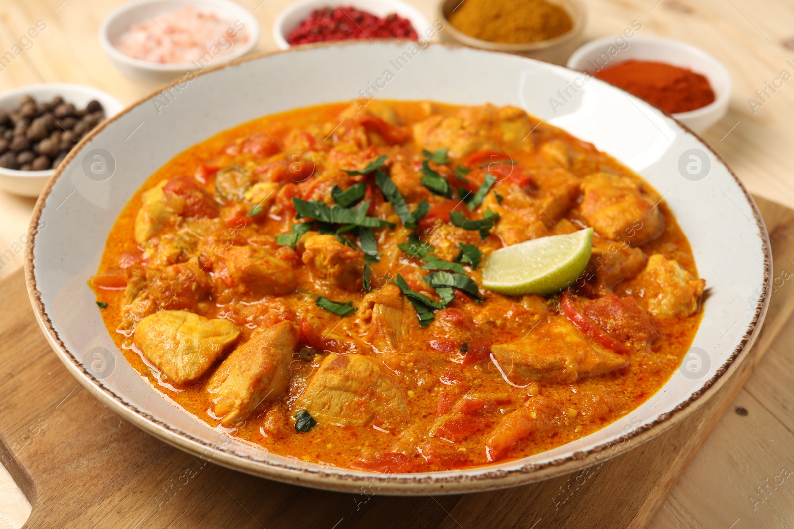 Photo of Delicious chicken curry and spices on table, closeup