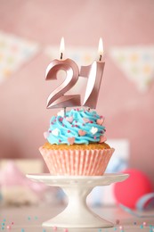 Photo of 21th birthday. Delicious cupcake with number shaped candles for coming of age party on white table