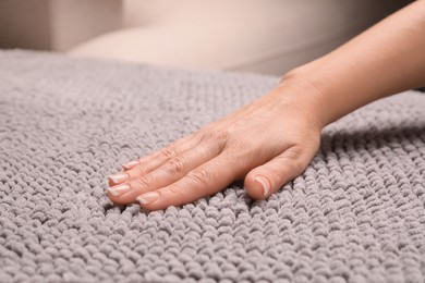 Woman touching soft grey fabric indoors, closeup