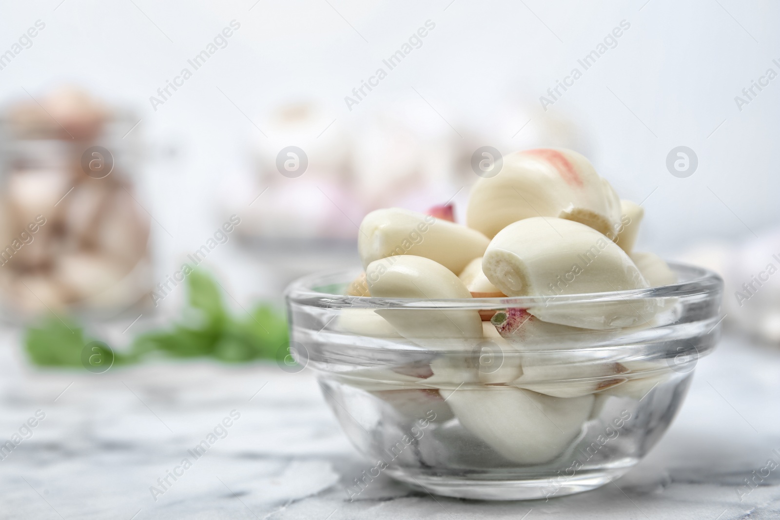 Photo of Glass bowl with ripe garlic cloves on table