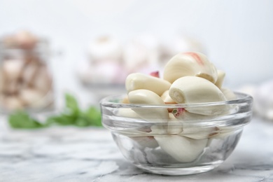 Glass bowl with ripe garlic cloves on table