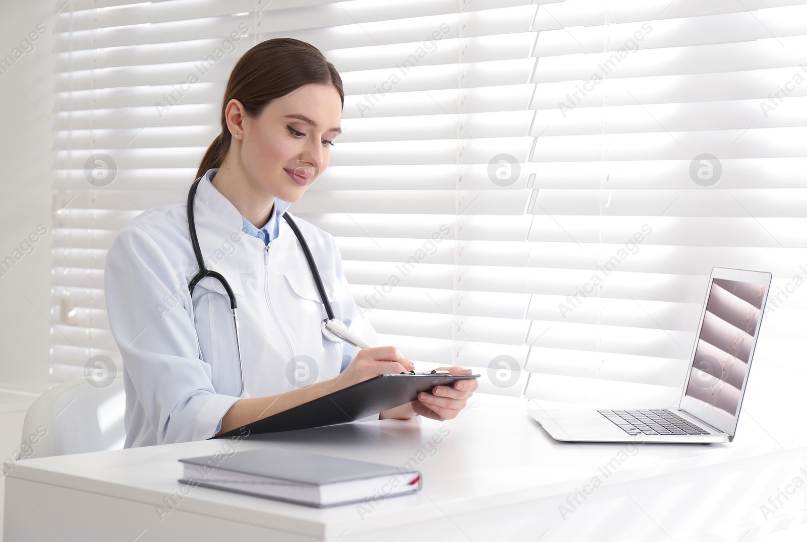 Photo of Young female doctor working at table in office