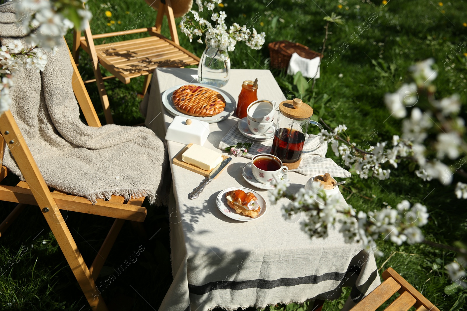 Photo of Beautiful table setting with spring flowers in garden on sunny day