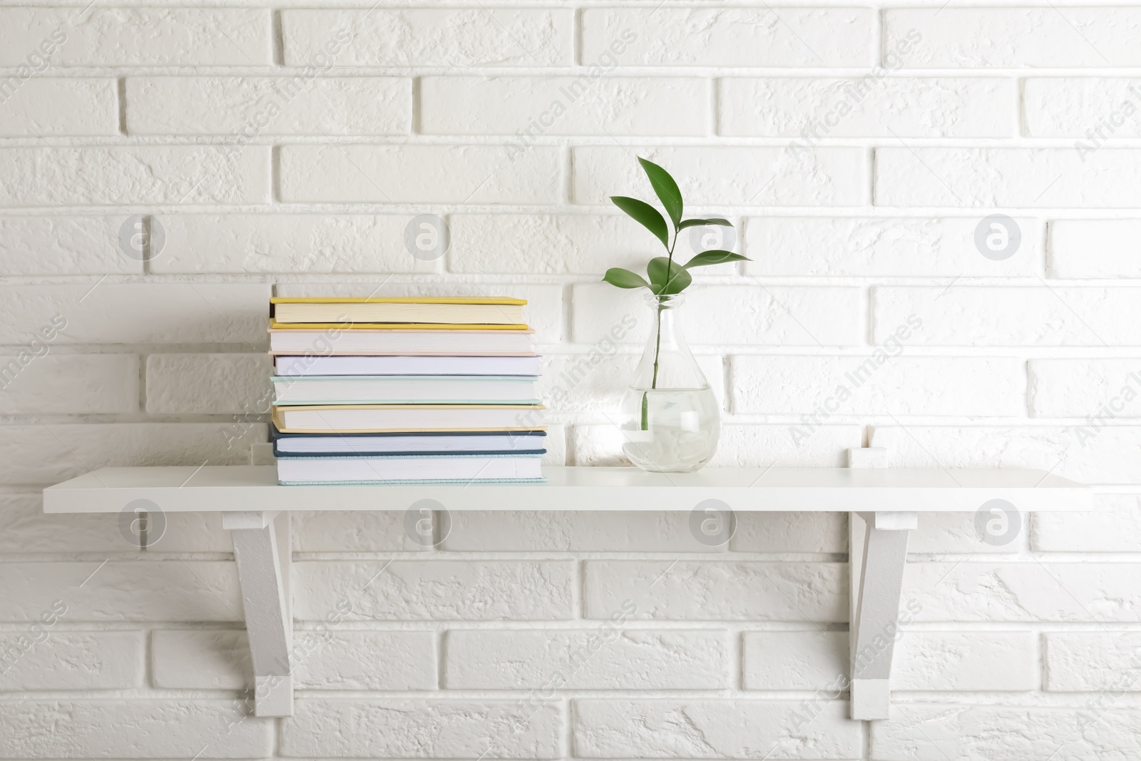 Photo of Shelf with stack of hardcover books hanging on brick wall