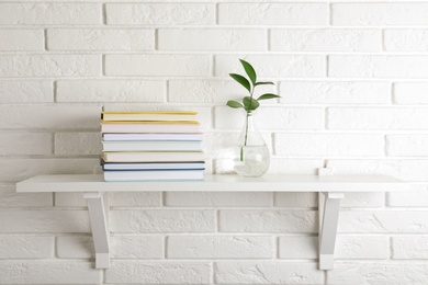 Photo of Shelf with stack of hardcover books hanging on brick wall