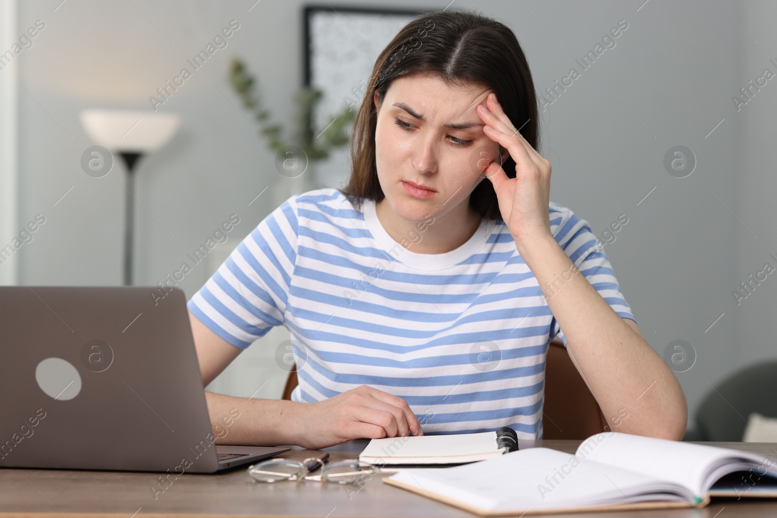 Photo of Overwhelmed woman sitting with laptop at table indoors