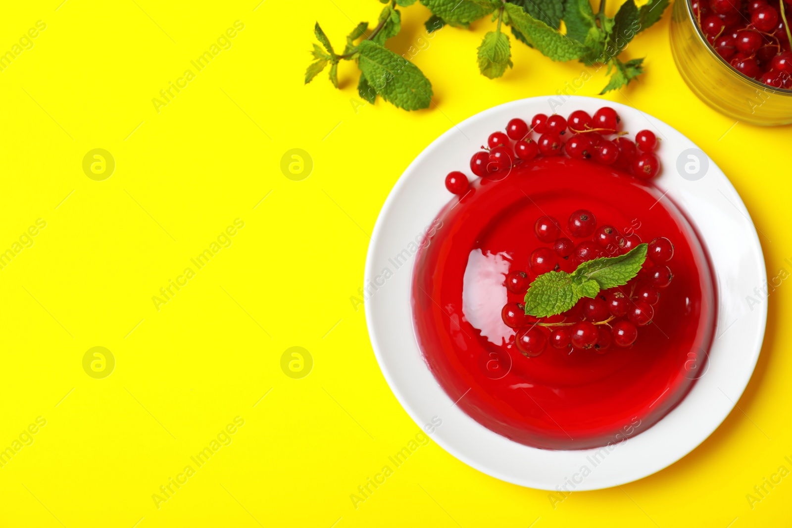 Photo of Delicious fresh red jelly with berries and mint on yellow background, flat lay. Space for text